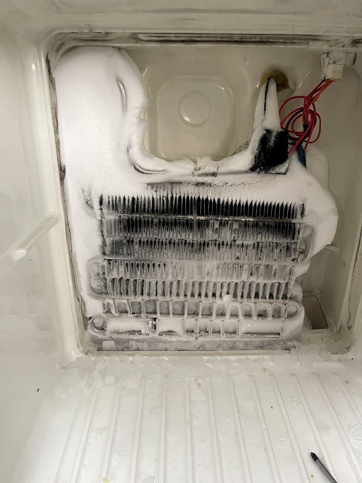 Evaporator covered in frost behind the freezer panel, a sign of a defrost fault