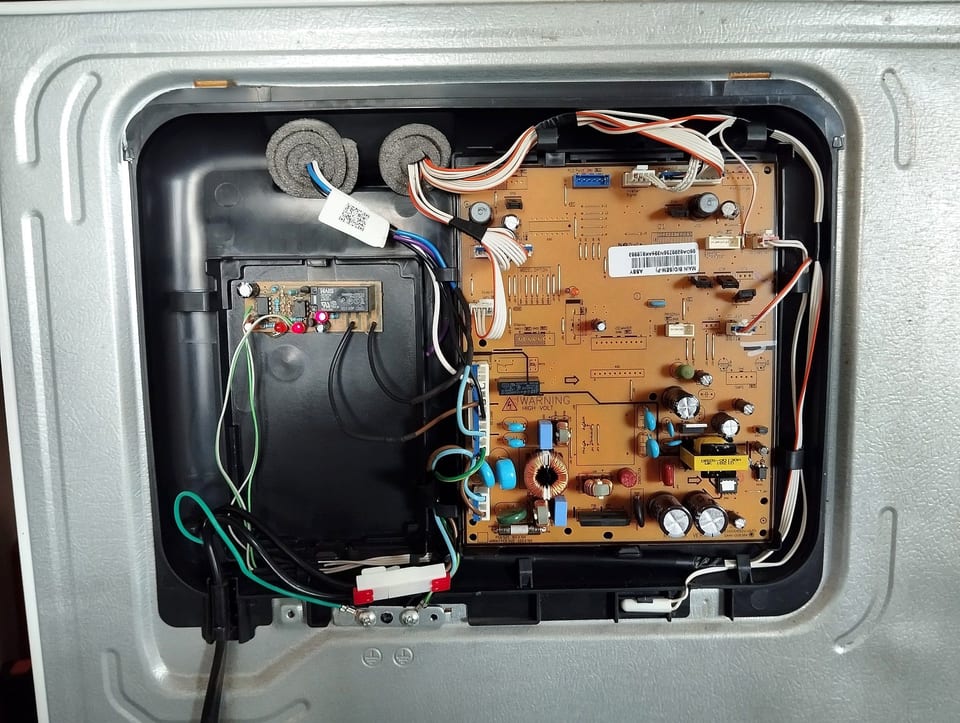 Main control board and wiring behind a refrigerator's rear cover